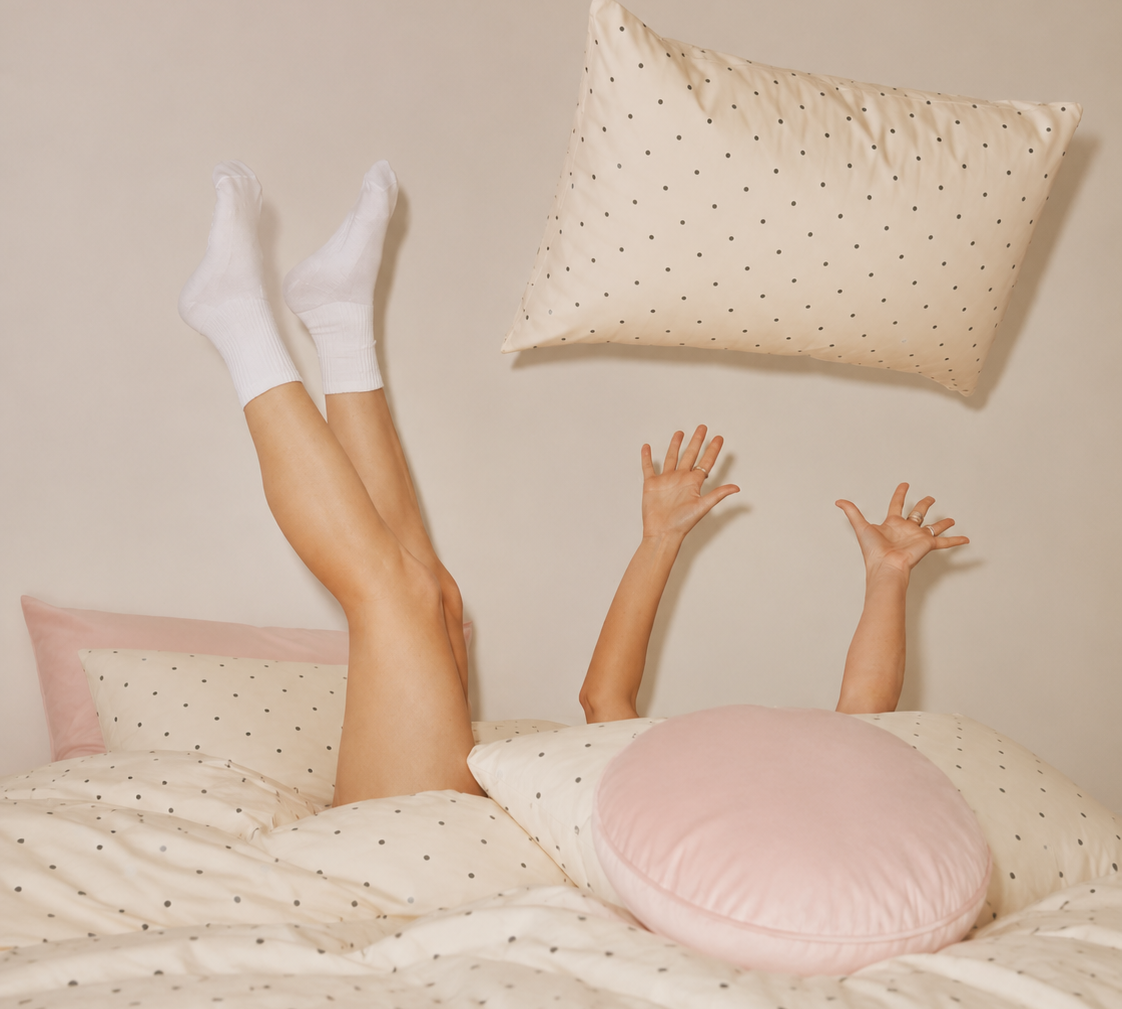 Playful shot on the Lenny Spot Bedding Set, cream spot cotton with a blush pink pillowcase edge and cushion