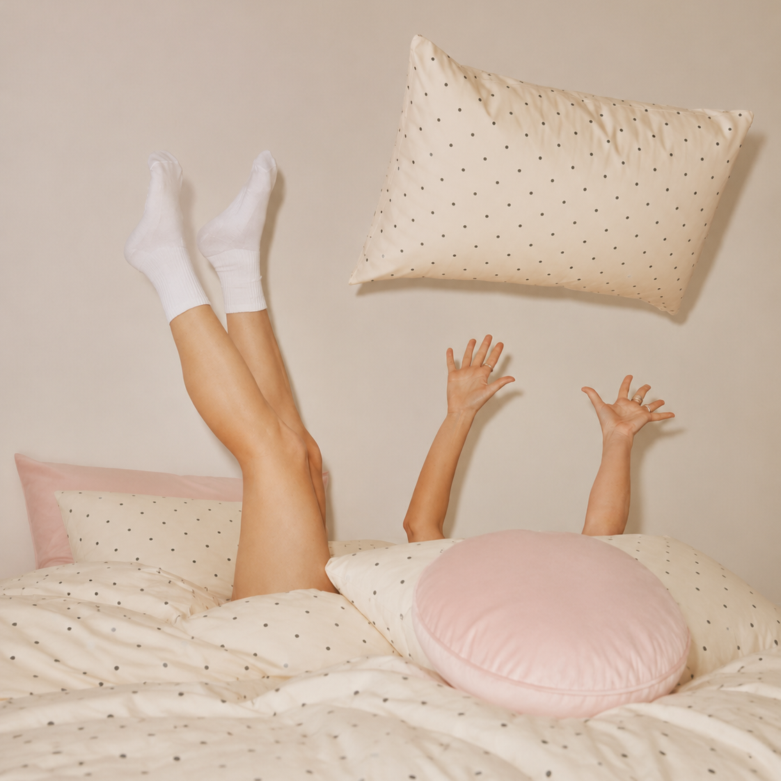 Playful shot on the Lenny Spot Bedding Set, cream spot cotton with a blush pink pillowcase edge and cushion