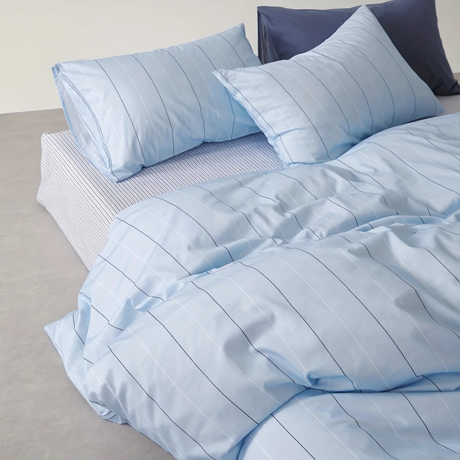 Aero Stripe Bedding Set in pale blue with fine pinstripes, shown on a bed with matching pillowcases