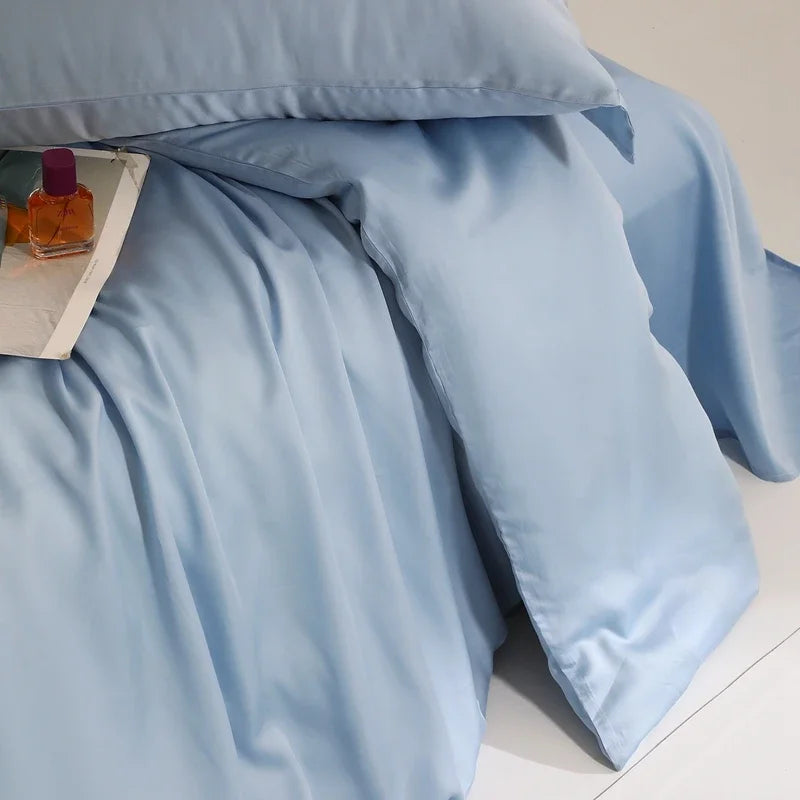 Close-up of the Agnes Silk Bedding Set in pale blue, showing soft sheen and draped folds on a bed