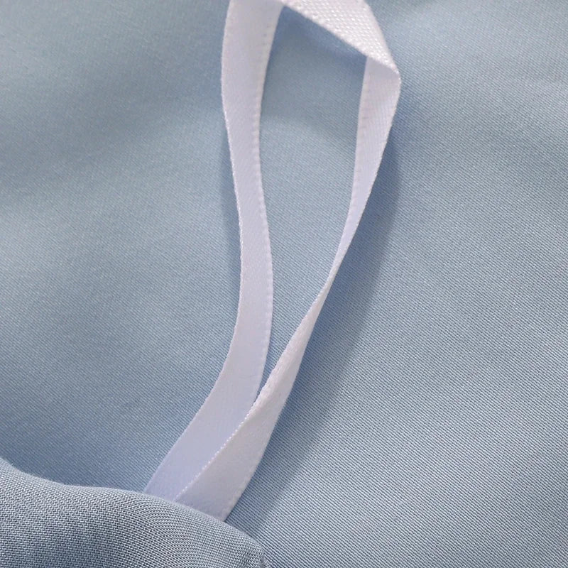 Close-up of an interior tie loop and buttery sheen on the pale blue Agnes Silk Bedding Set