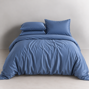 Agnes Silk Bedding Set in Midnight Blue on a made bed, showing the silk's soft sheen and draped folds