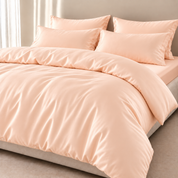 Agnes Silk Bedding Set in Peach Sorbet, made bed with soft sheen and buttoned quilt cover closure