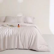 Agnes Silk Bedding Set in Pearl White, made bed with silky sheen, magazine and perfume styled on top