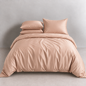 Agnes Silk Bedding Set in Rose Gold, made bed with silk quilt cover and pillowcases showing a soft sheen