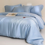 Agnes Silk Bedding Set in pale blue, made bed with silky sheen and soft folds, magazine styled on top