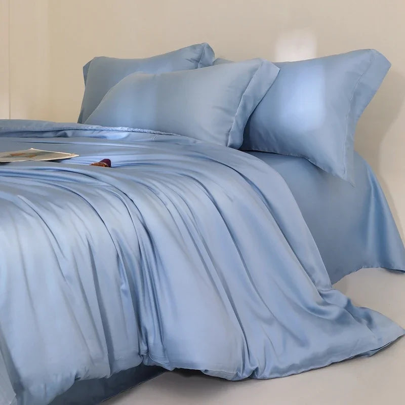 Agnes Silk Bedding Set in soft blue, draped in loose folds across a made bed with plump pillows