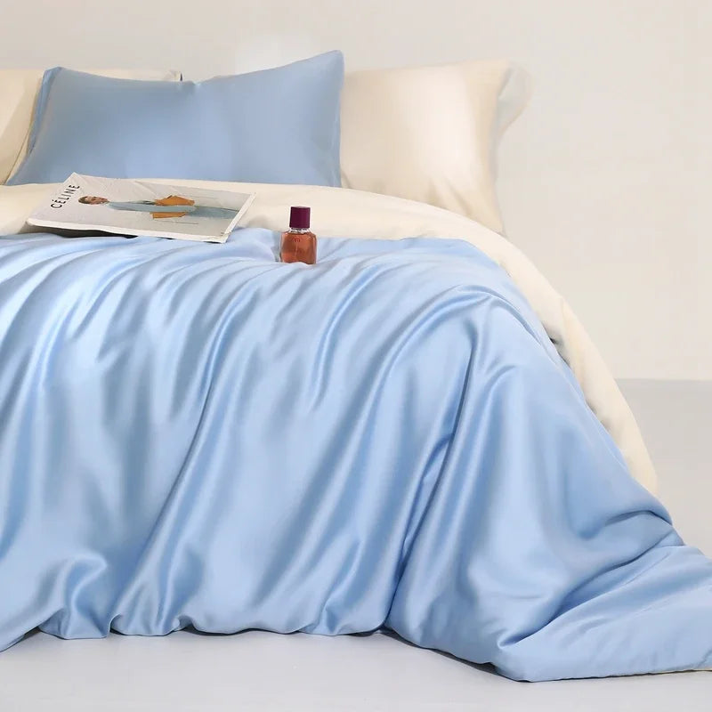 Agnes Silk Bedding Set in pale blue with cream reverse, softly draped on a bed with a magazine styled on top