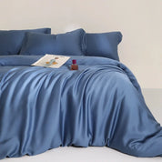 Agnes Silk Bedding Set in deep blue, silky sheen catches light across a draped quilt cover on a bed