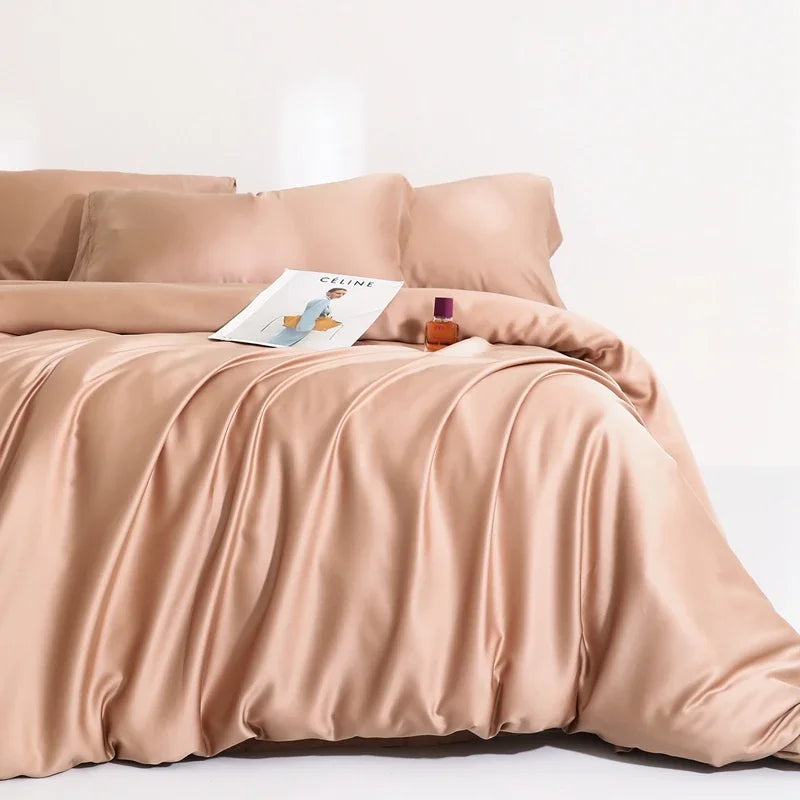 Agnes Silk Bedding Set in soft peach, draped in loose folds on a bed with a magazine styled on top