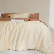 Agnes Silk Bedding Set in cream with caramel pillowcase edges, soft draped folds on a made bed