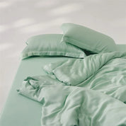 Amélie Bedding Set in soft sage green, rumpled quilt cover and pillowcases with a silky sheen