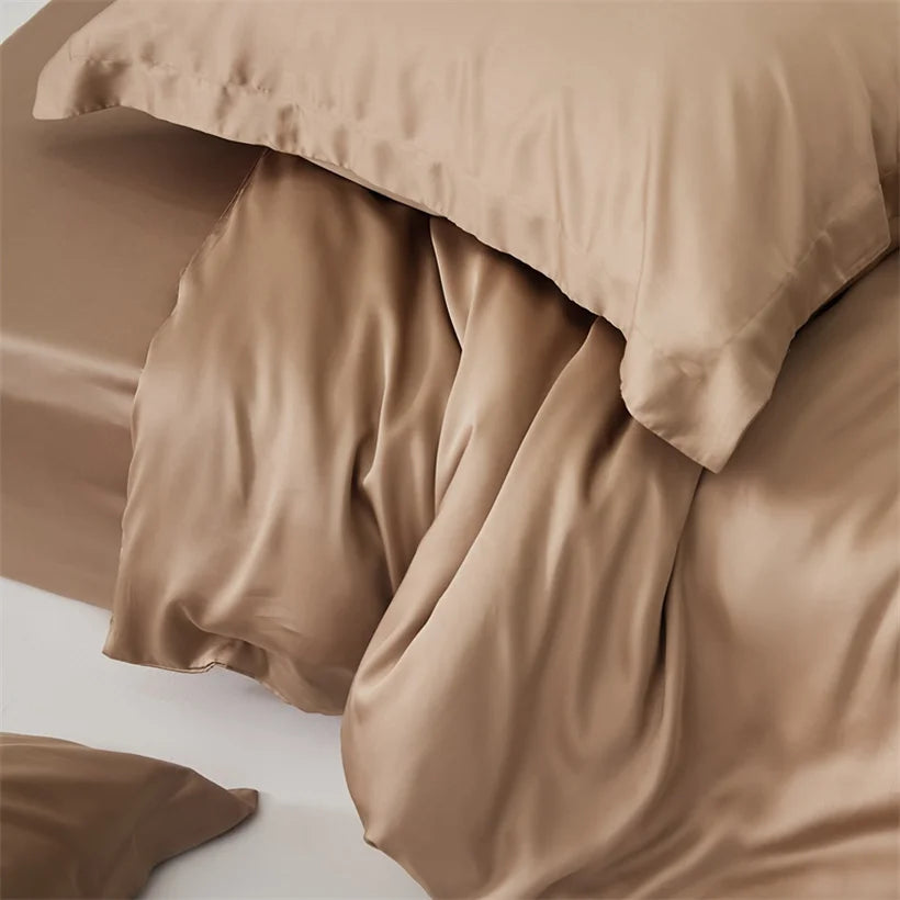 Close-up of the Amélie Bedding Set in warm sandy tan, lyocell silk pooling in soft folds with a subtle sheen