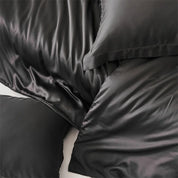 Close-up of Amélie Bedding Set in deep charcoal-black, showing the lyocell silk's soft sheen and folds