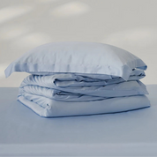 Amélie Bedding Set folded in a stack, pale blue lyocell silk with a soft sheen, pillowcase on top