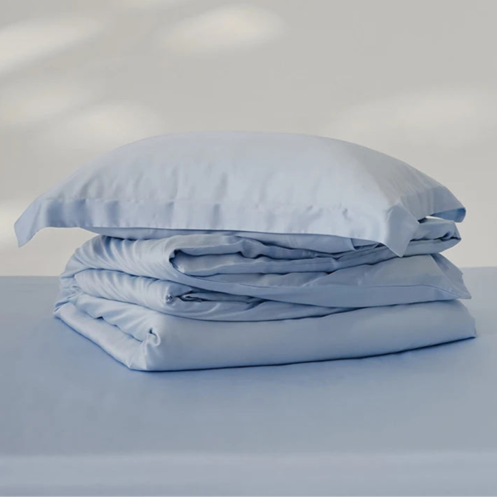 Amélie Bedding Set folded in a stack, pale blue lyocell silk with a soft sheen, pillowcase on top