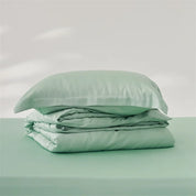 Amélie Bedding Set folded in soft mint green, quilt cover and pillowcase stacked showing silky sheen