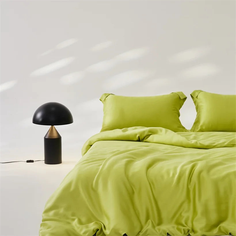Amélie Bedding Set in Lime Sorbet, made bed with sheen lyocell silk quilt cover, black mushroom lamp beside
