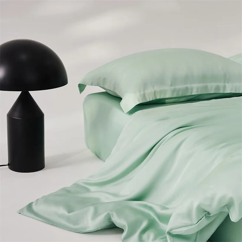 Amélie Bedding Set in Mint, sheeny lyocell silk draped loosely beside a black mushroom lamp