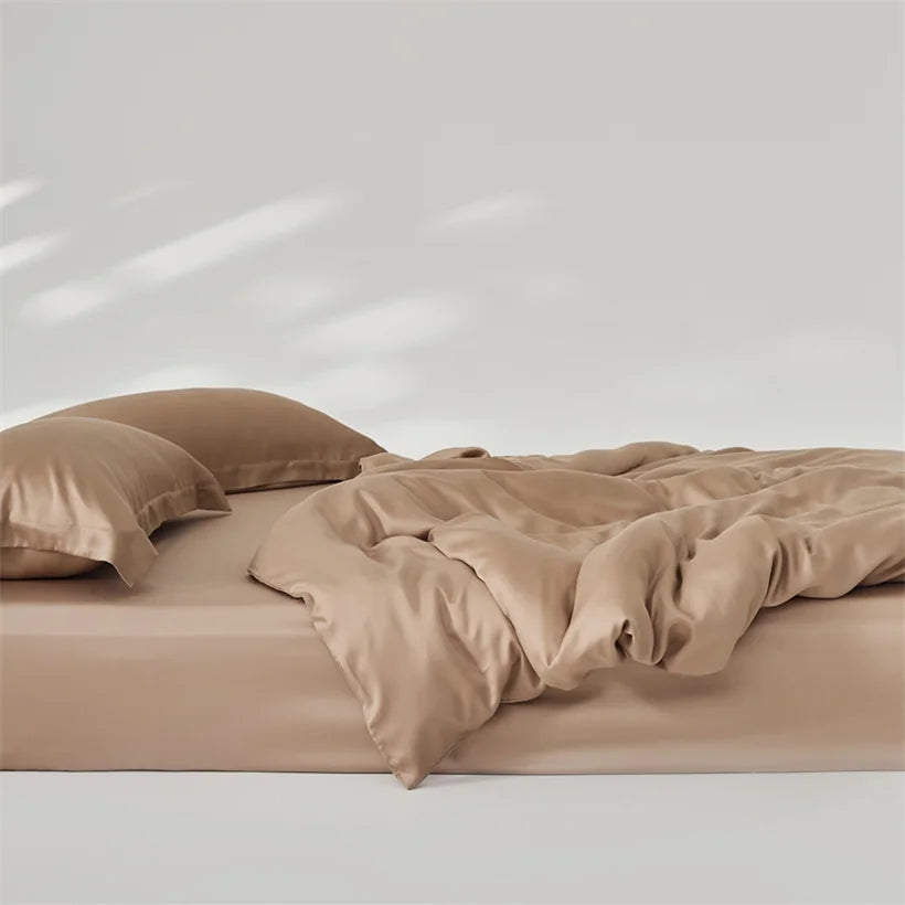 Amélie Bedding Set in Sandstone, rumpled quilt cover and pillowcases showing soft sheen on a bare mattress