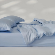 Amélie Bedding Set in soft pale blue, quilt cover loosely draped over a bed with matching pillowcases