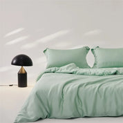 Amélie Bedding Set styled on a bed in soft mint green, with a mushroom-shaped lamp beside it