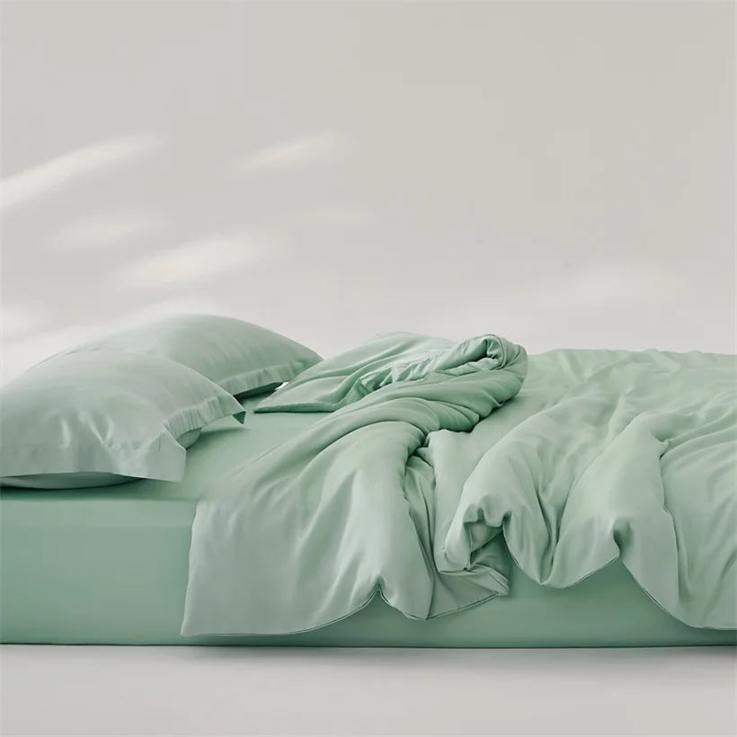Amélie Bedding Set in soft sage green, quilt cover loosely rumpled atop fitted sheet and pillow