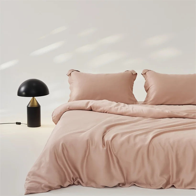 Amélie Bedding Set in dusty pink lyocell silk, styled on a bed with a black mushroom lamp beside it