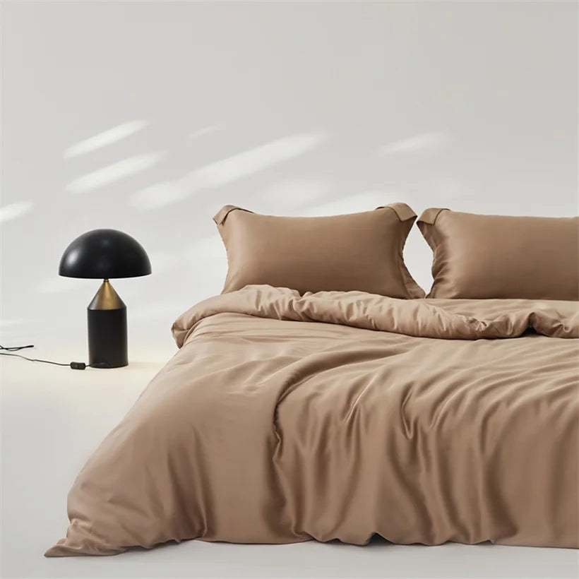 Amélie Bedding Set in warm sandy taupe, sheen catching soft light beside a black mushroom lamp