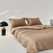 Amélie Bedding Set styled on a bed in warm sandstone tan, with a mushroom lamp beside it