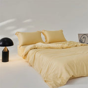 Amélie Bedding Set in soft golden yellow, styled on a made bed with a black lamp and line-art print nearby