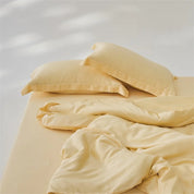 Amélie Bedding Set in soft buttery yellow, pillowcases and quilt cover rumpled on an unmade bed