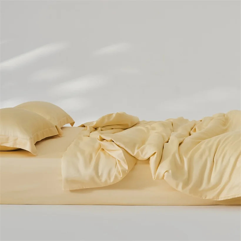 Amélie Bedding Set rumpled loosely on a bed, soft golden-yellow lyocell silk catching gentle light
