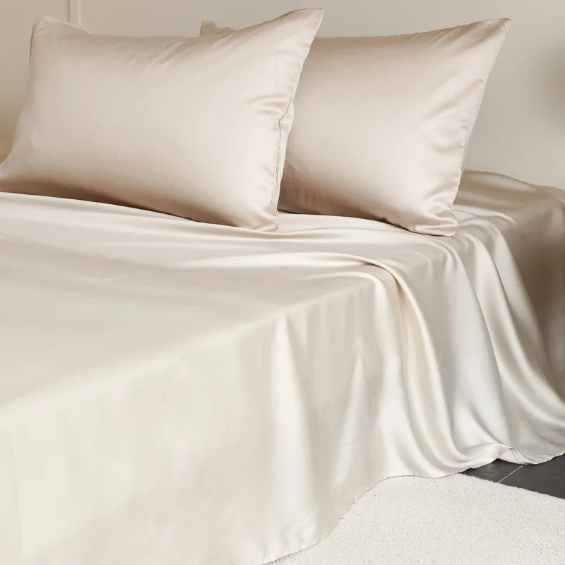Amélie Flat Sheet Set in Champagne Gold, silky lyocell sheet and pillowcases draped over a made bed