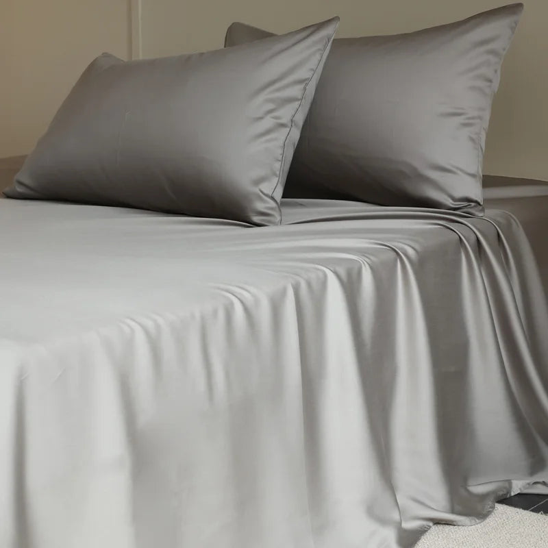 Amélie Flat Sheet Set in Dove Grey, draped over a bed with soft folds and lustrous sheen