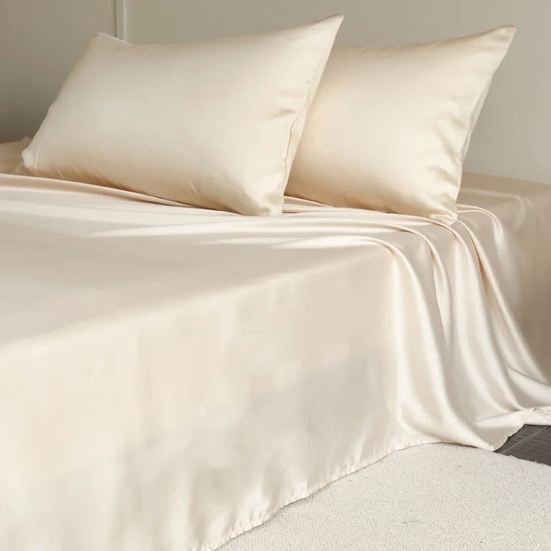 Amélie Flat Sheet Set in Golden Butter, draped over a made bed with soft lyocell silk sheen and pillowcases