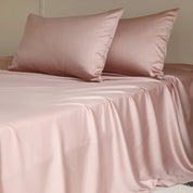 Amélie Flat Sheet Set in Petal Pink, made bed with soft sheen and draped folds of lyocell silk