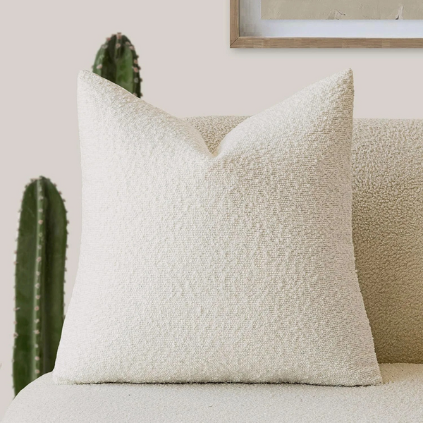 Archie Boucle Cushion in White, looped bouclé texture on a beige sofa beside a cactus