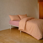 Avery Gingham Bedding Set in peach and yellow check, folded back over a pink cotton sheet