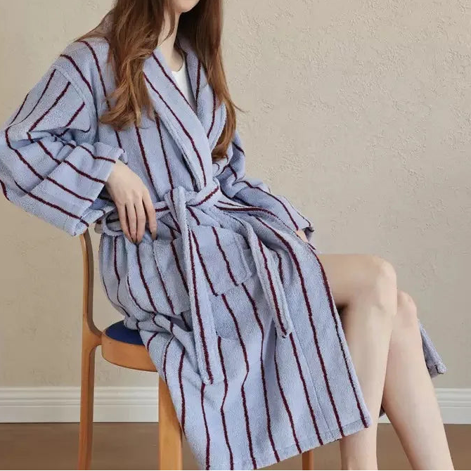 Seated model wears the Bambi Striped Bath Robe in pale blue with burgundy stripes, tied at the waist