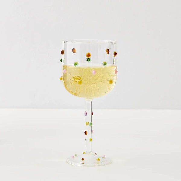 Billie Wine Glass in Clear, filled with sparkling wine, multicoloured dots on bowl and stem