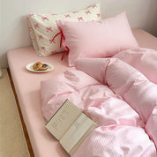Blossom Bow Bedding Set in Blush, pink striped quilt cover and bow-tied pillowcase styled with book and donuts