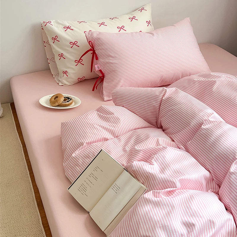 Blossom Bow Bedding Set in Blush, pink striped quilt cover and bow-tied pillowcase styled with book and donuts