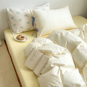 Blossom Bow Bedding Set in Lemon, striped quilt cover styled on a bed with a bow-print pillowcase and book