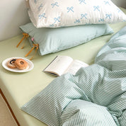 Blossom Bow Bedding Set in Mint, striped quilt cover with bow ties beside a bagel plate and open book