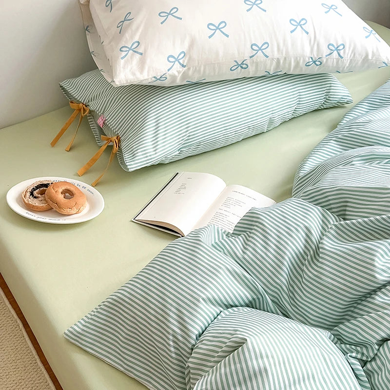 Blossom Bow Bedding Set in Mint, striped quilt cover with bow ties beside a bagel plate and open book