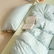 Blossom Bow Bedding Set in Mint, striped quilt cover with bow ties, open book resting on rumpled bed