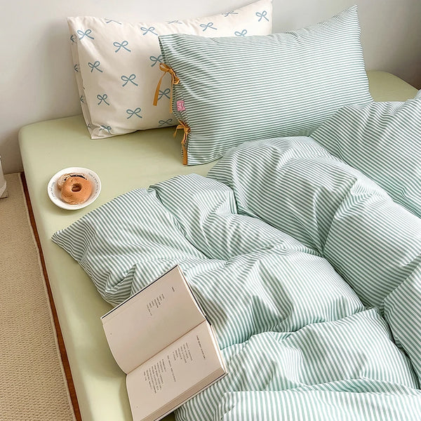 Blossom Bow Bedding Set in Mint, striped quilt cover on a bed with an open book and pastry
