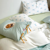 Blossom Bow Bedding Set styled with mint stripe and blue bow-print pillowcases, mustard tie detail, pastries on plate