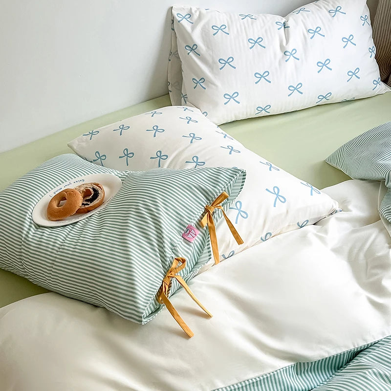 Blossom Bow Bedding Set styled with mint stripe and blue bow-print pillowcases, mustard tie detail, pastries on plate
